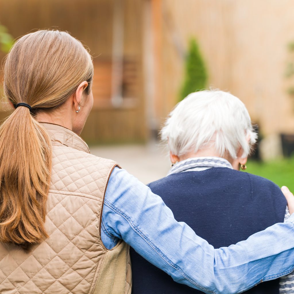 Young carer walking with the elderly woman in the park